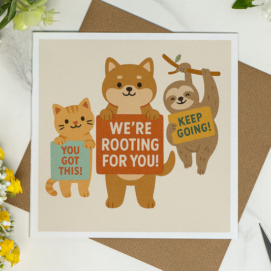 Square encouragement card featuring a cat, dog, and sloth holding signs that say “You Got This!”, “We’re Rooting For You!”, and “Keep Going!”. Printed on white 144 x 144mm card with a kraft envelope. A cute and uplifting card for support, motivation, or tough times.