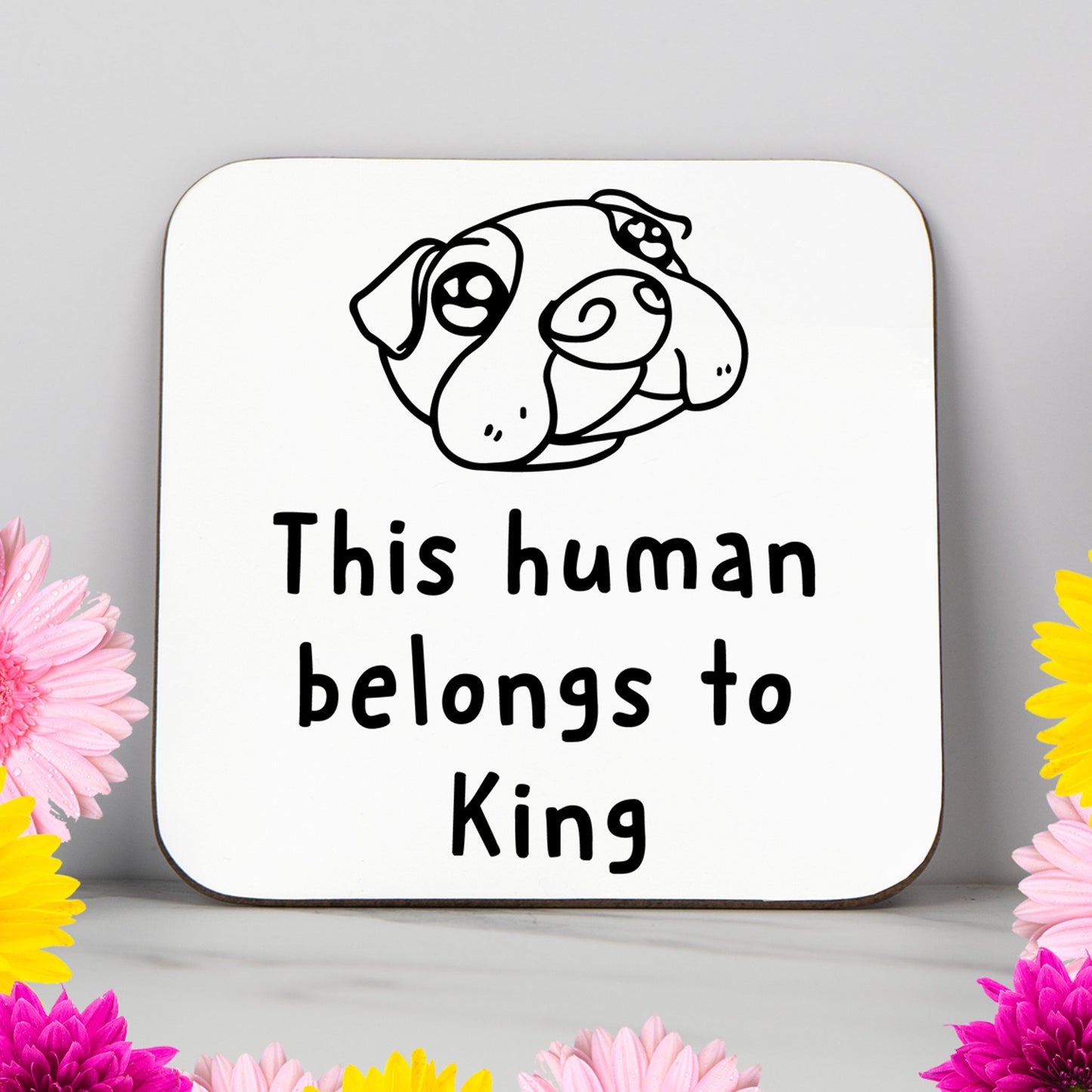 White coaster featuring a cartoon dog face and the phrase “This human belongs to King.” A personalised gift for dog owners, dog mums, and dog dads, perfect for birthdays or pet lovers.