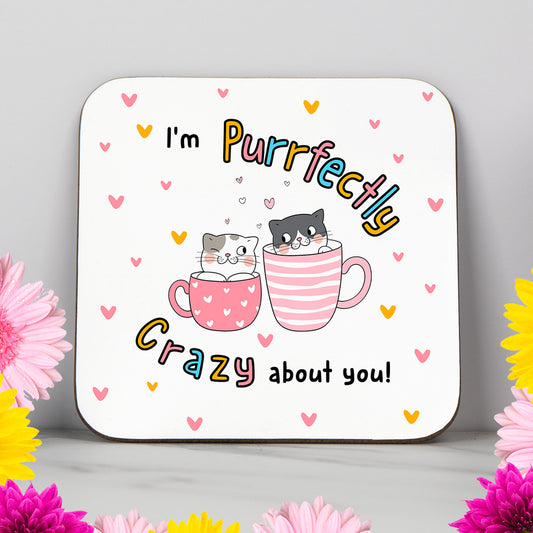 Valentine's Day coaster featuring two cute cartoon cats sitting in heart-covered mugs with the phrase "I'm Purrfectly Crazy About You." Surrounded by pink and yellow hearts, this adorable design is perfect for cat lovers, couples, or anyone who loves romantic, funny, or pun-themed gifts. A sweet and light-hearted present for a girlfriend, boyfriend, husband, wife, or partner. Ideal for Valentine’s Day, anniversaries, or just because.